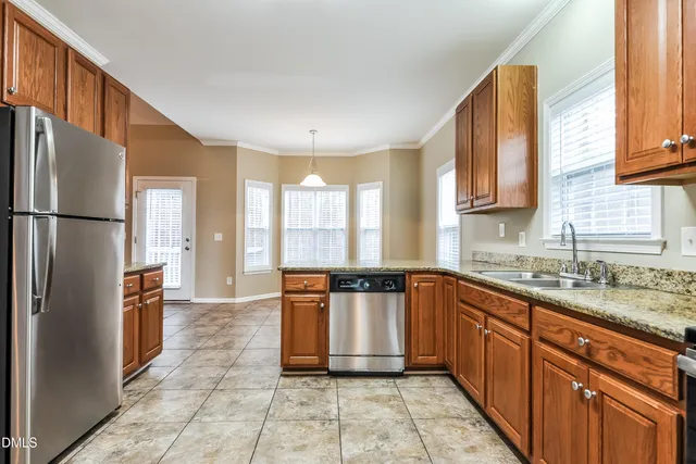 a kitchen with stainless steel appliances granite countertop a refrigerator a sink a stove with wooden cabinets