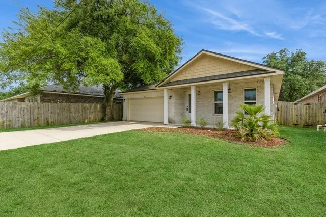 a view of a house with a yard and a large tree