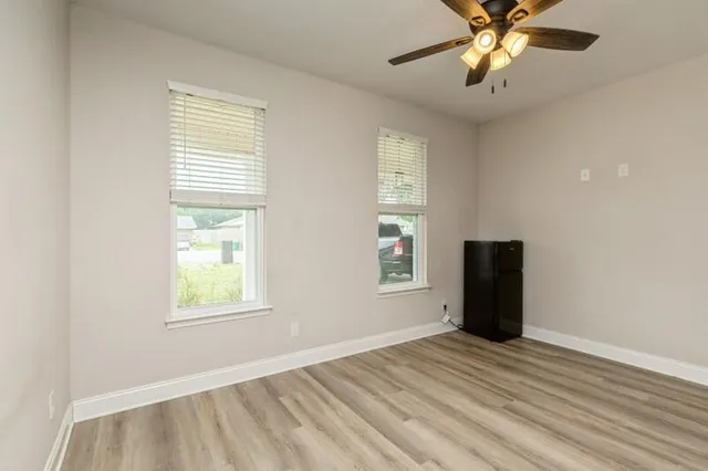 a view of an empty room with a window and wooden floor