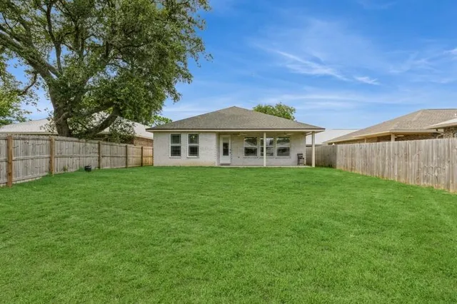 a view of a yard in front of a house with large trees
