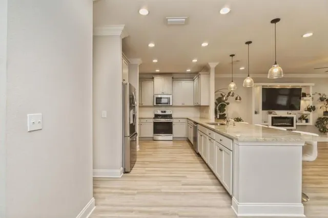 a large kitchen with granite countertop a large counter top a sink stainless steel appliances and cabinets