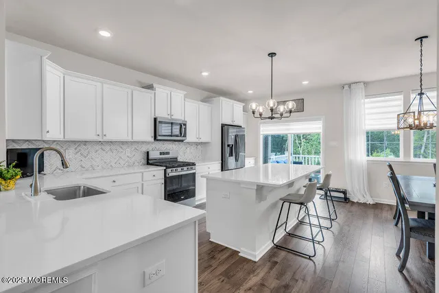 a kitchen with stainless steel appliances granite countertop a stove top oven a sink dishwasher a dining table and chairs with wooden floor