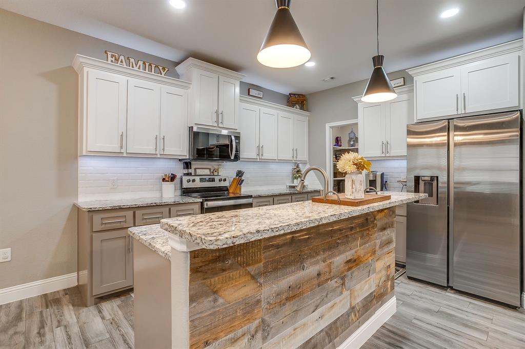 409 Titus Drive Springtown, TX 76082 - Photo 12 of 39 a kitchen with granite countertop a refrigerator a sink a stove a microwave a counter space and cabinets