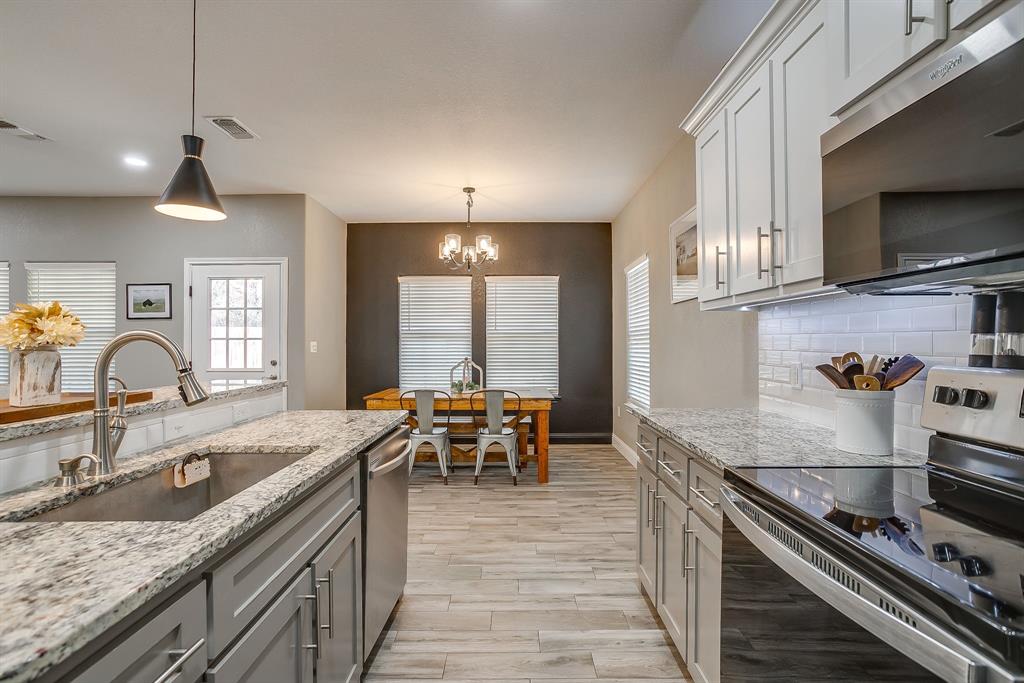 409 Titus Drive Springtown, TX 76082 - Photo 13 of 39 a kitchen with granite countertop lots of counter top space and stainless steel appliances