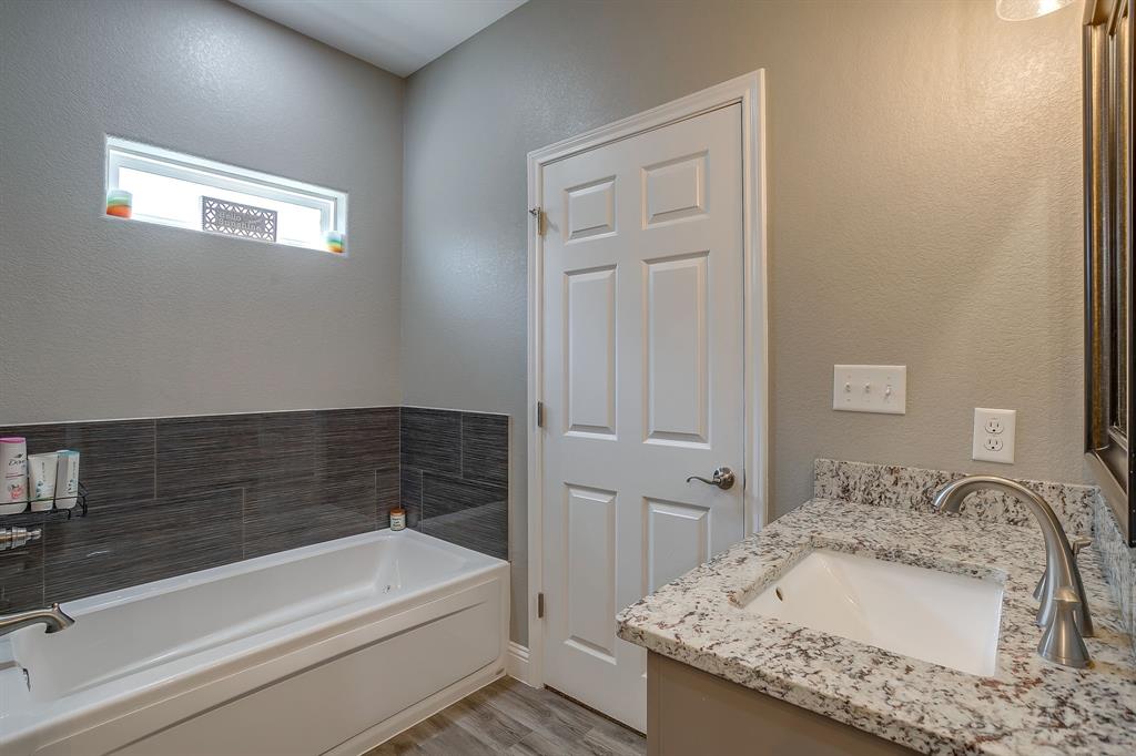 409 Titus Drive Springtown, TX 76082 - Photo 25 of 39 a bathroom with a granite countertop sink and a bathtub