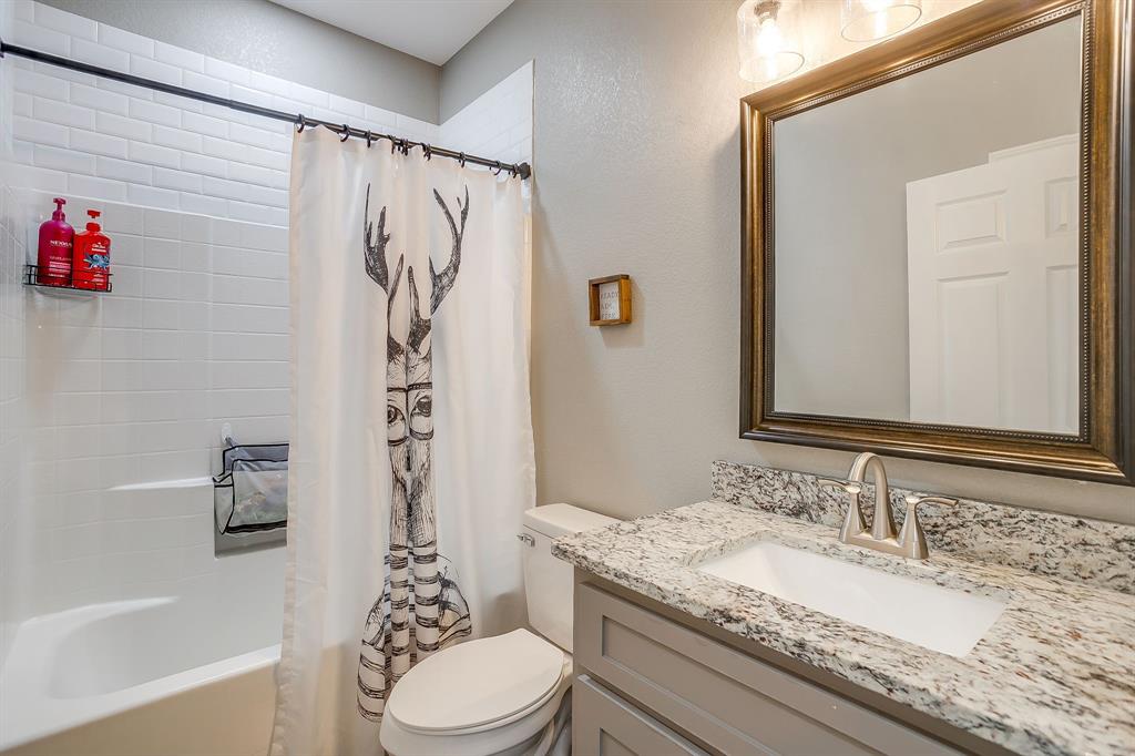 409 Titus Drive Springtown, TX 76082 - Photo 32 of 39 a bathroom with a granite countertop sink a toilet and a bathtub