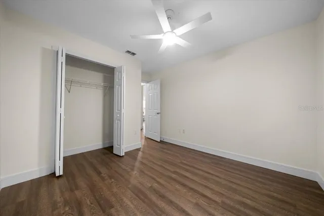 an empty room with wooden floor and a ceiling fan