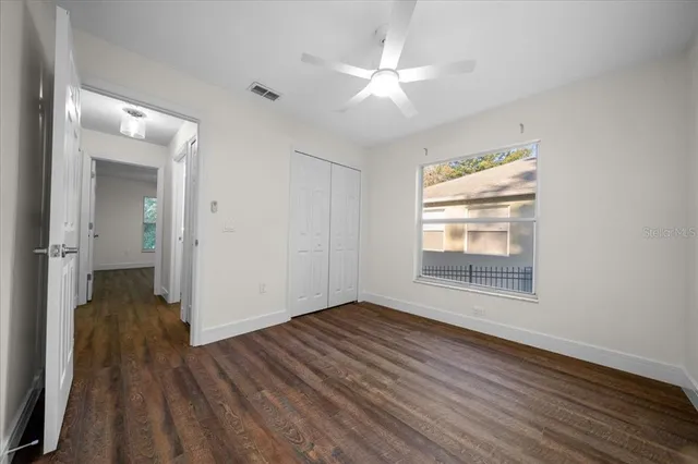 an empty room with wooden floor and a ceiling fan