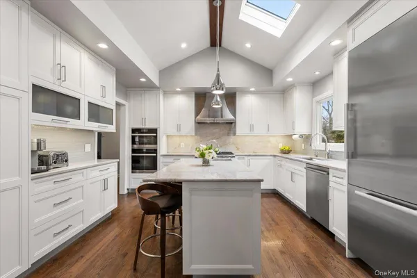 a kitchen with stainless steel appliances kitchen island granite countertop a stove a sink and a refrigerator