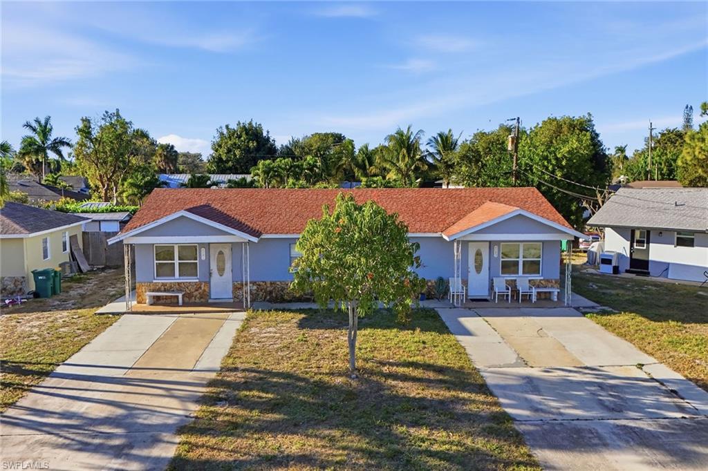 Bungalow with stone siding, a front lawn, driveway, and stucco siding