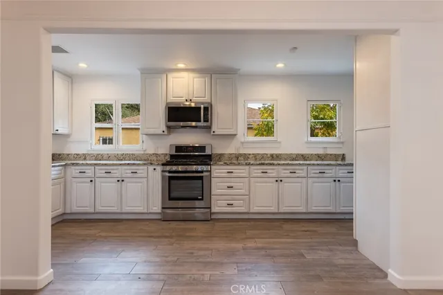 a kitchen with granite countertop white cabinets and appliances