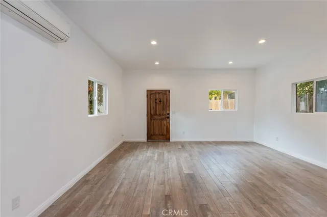 a view of an empty room with a window and wooden floor