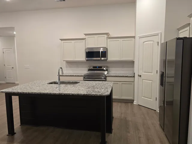 a kitchen with stainless steel appliances granite countertop wooden cabinets a refrigerator and a sink