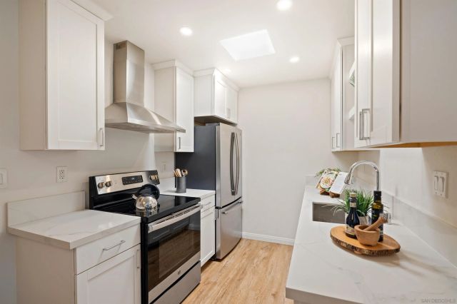 a kitchen with stainless steel appliances granite countertop a refrigerator a stove a sink and white cabinets