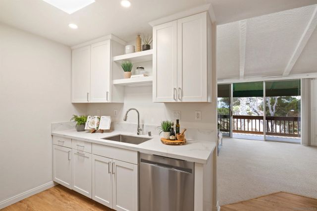 a kitchen with stainless steel appliances granite countertop a sink a stove and white cabinets