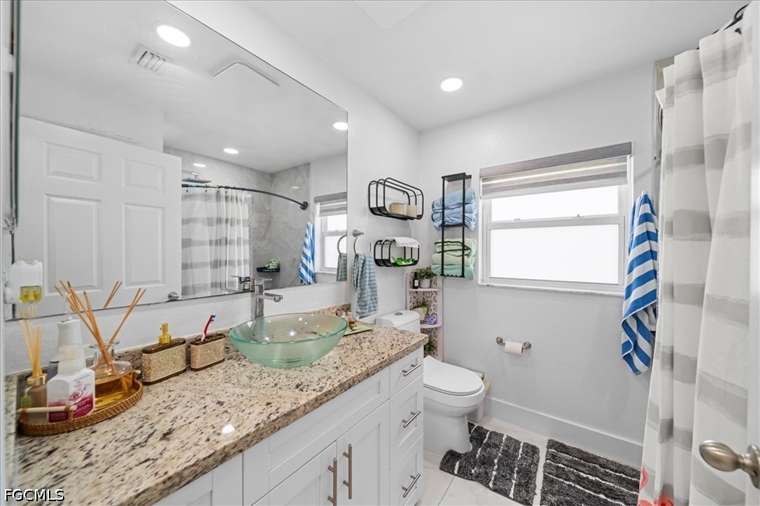 22 Nelson Road South Cape Coral, FL 33991 - Photo 21 of 43 a bathroom with a granite countertop sink a toilet and a shower