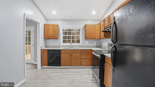 a kitchen with stainless steel appliances granite countertop a sink and a refrigerator