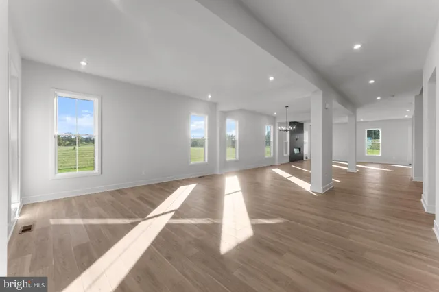 a view of an empty room with window and wooden floor