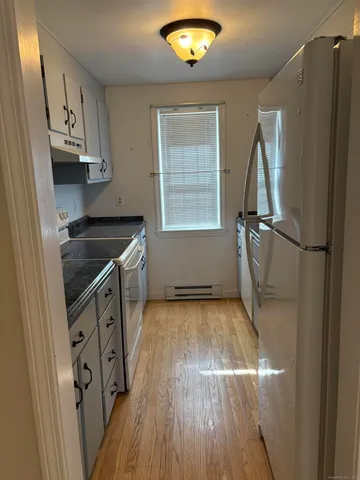 a kitchen with granite countertop white cabinets and wooden floor