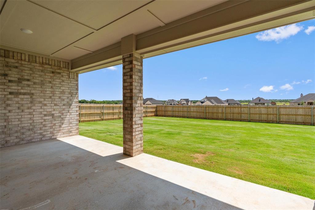 1341 Promised Land Road Hewitt, TX 76643 - Photo 24 of 29 Covered patio featuring a brick wall, concrete flooring, and recessed lighting, opening to a spacious lawn with a wood privacy fence