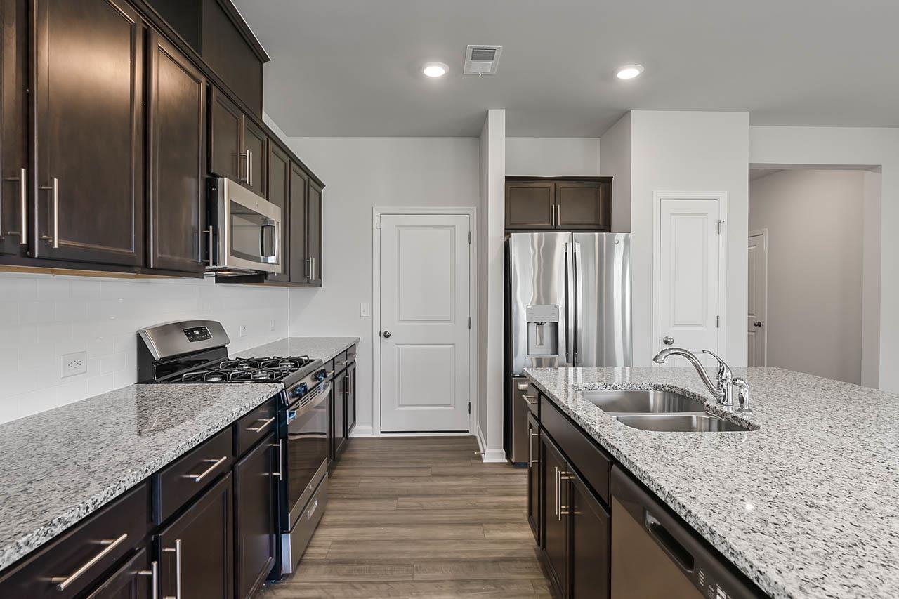 2421 Chert Lane Raleigh, NC 27610 - Photo 21 of 97 a kitchen with granite countertop kitchen island stainless steel appliances a sink stove top oven and refrigerator