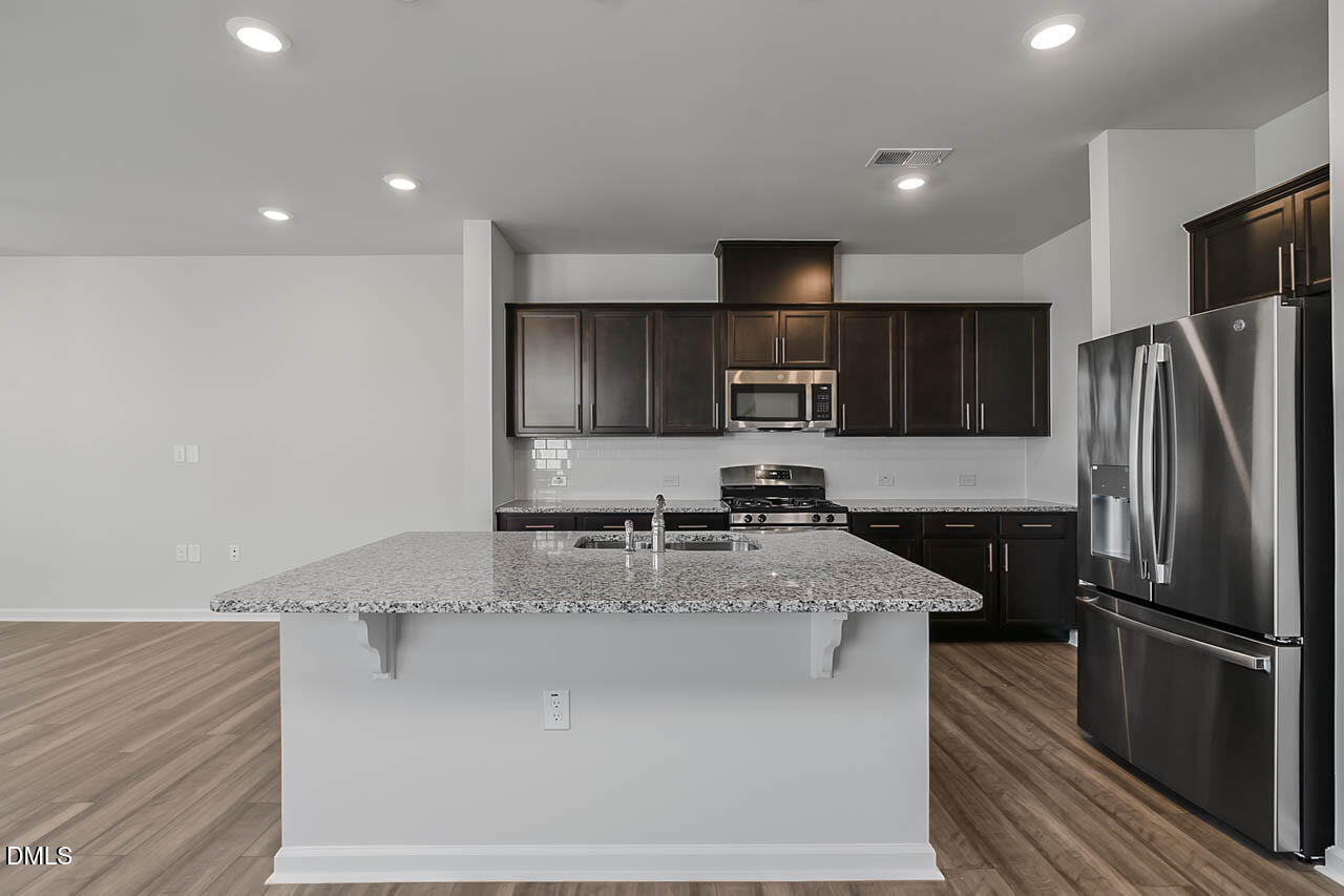 2421 Chert Lane Raleigh, NC 27610 - Photo 78 of 97 a kitchen with stainless steel appliances granite countertop a refrigerator a stove and a sink with wooden cabinets