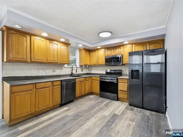 a kitchen with granite countertop stainless steel appliances a refrigerator cabinets and a sink