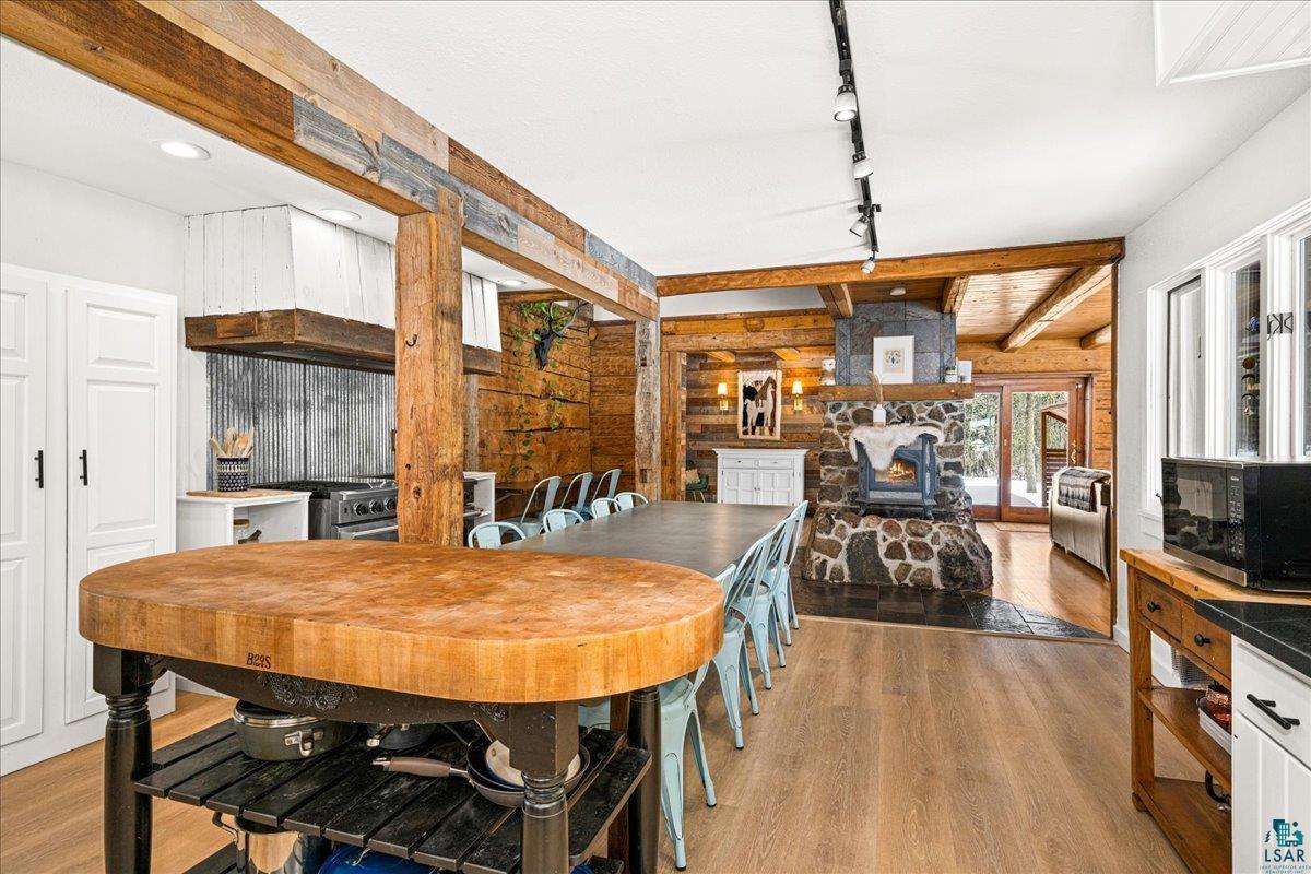 27 West Stark Road Esko, MN 55733 - Photo 14 of 47 Dining area with light wood-style floors, a wood stove, track lighting, and beam ceiling