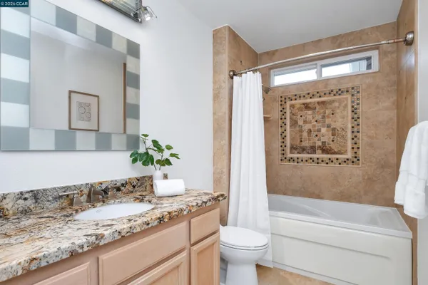 a bathroom with a granite countertop sink a toilet and bathtub