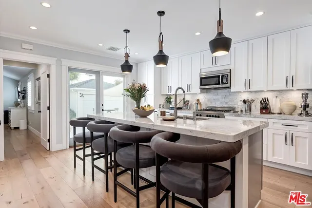 a kitchen with stainless steel appliances kitchen island granite countertop a table chairs sink and cabinets