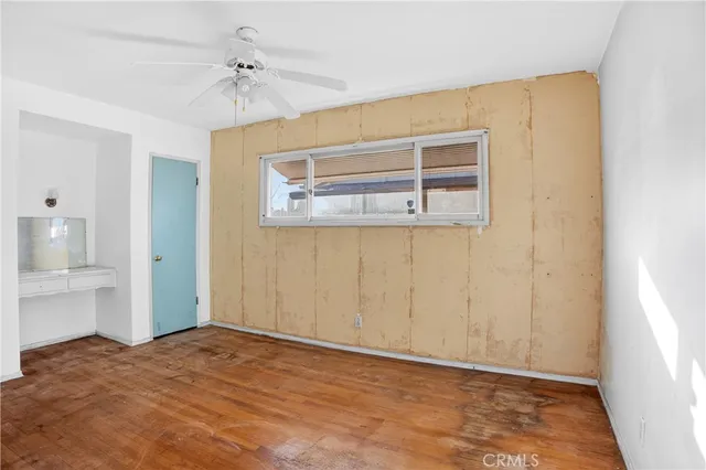 a view of empty room with wooden floor and fan