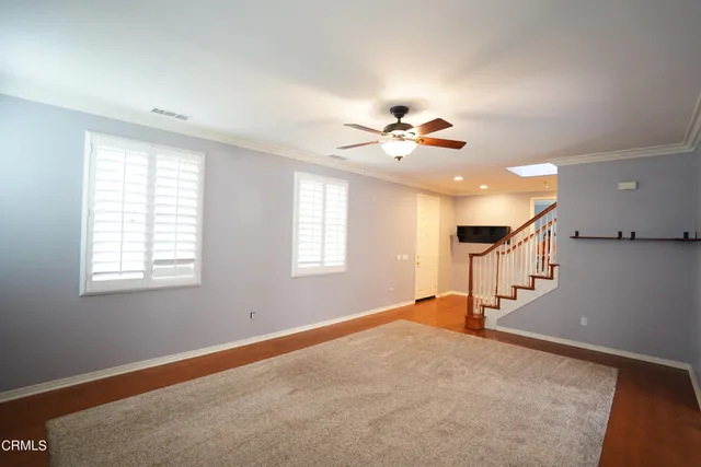a view of an empty room with window and wooden floor