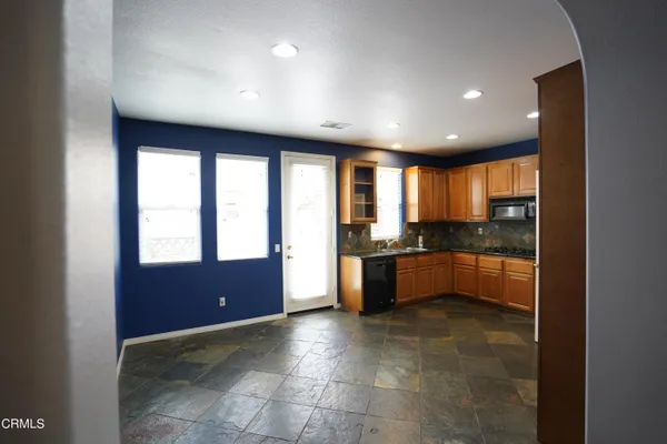 a large kitchen with stainless steel appliances granite countertop a refrigerator and a stove top oven