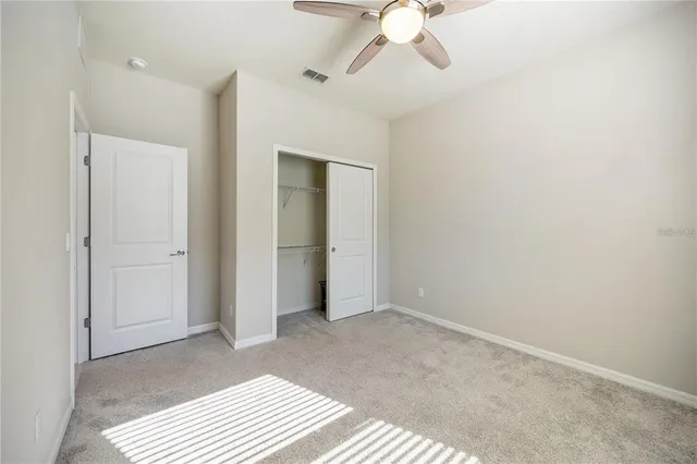 a view of an empty room with a chandelier fan