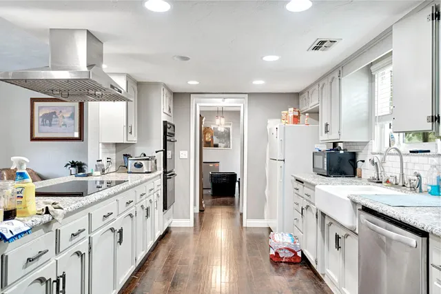 a kitchen with stainless steel appliances granite countertop a refrigerator sink and white cabinets