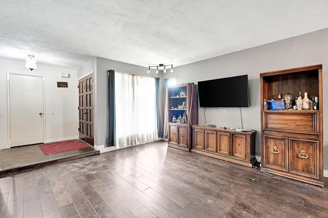 a view of a livingroom with entryway flat screen tv wooden floor and window