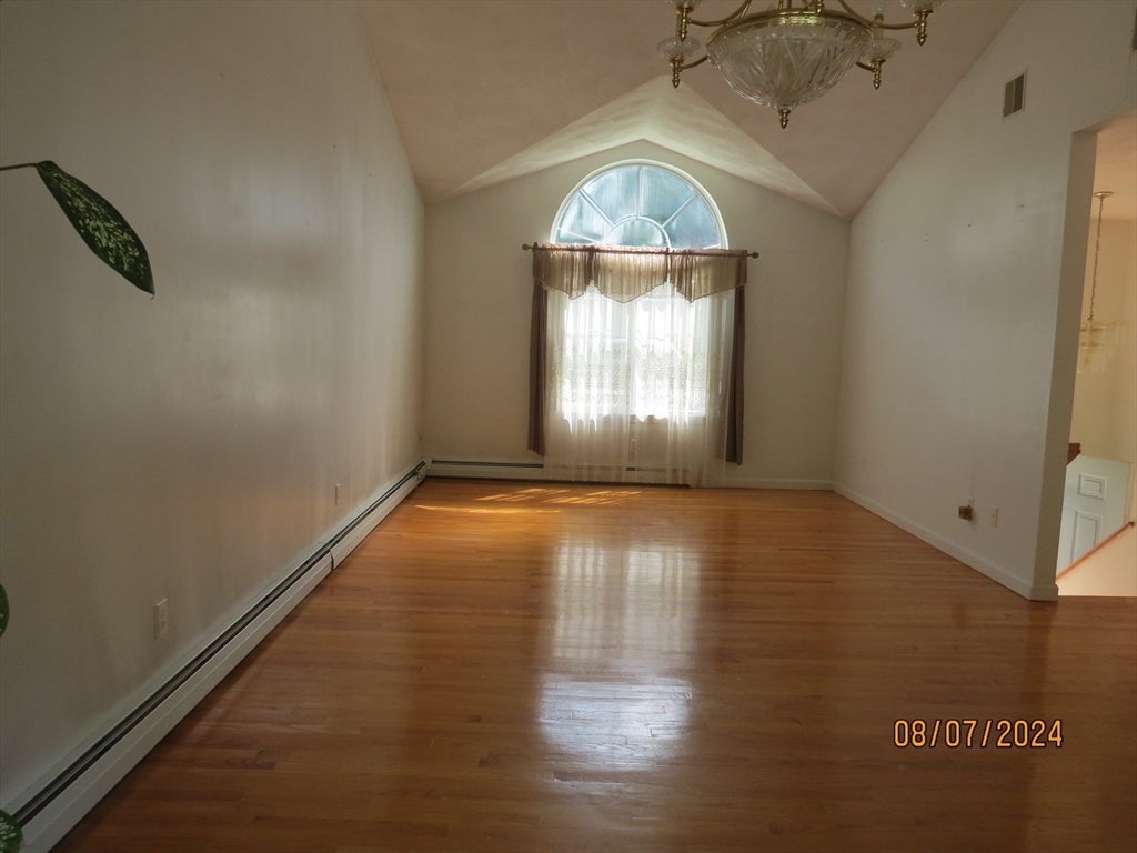 262 Acropolis Road Lowell, MA 01854 - Photo 4 of 31 an empty room with wooden floor chandelier and windows