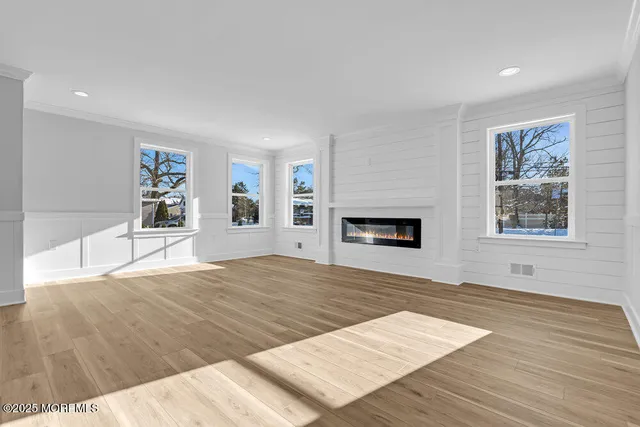 a view of empty room with wooden floor and window
