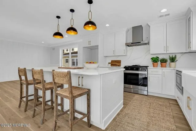 a kitchen with stainless steel appliances granite countertop a sink a stove a refrigerator and chairs