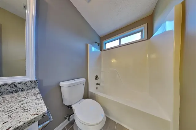 a bathroom with a granite countertop toilet a sink and a bathtub