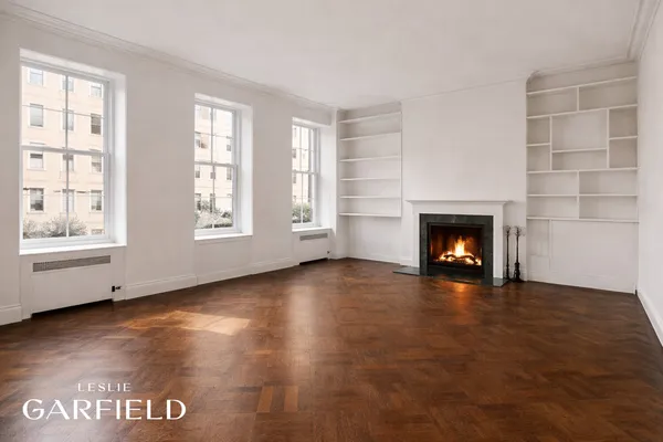 an empty room with windows and fireplace