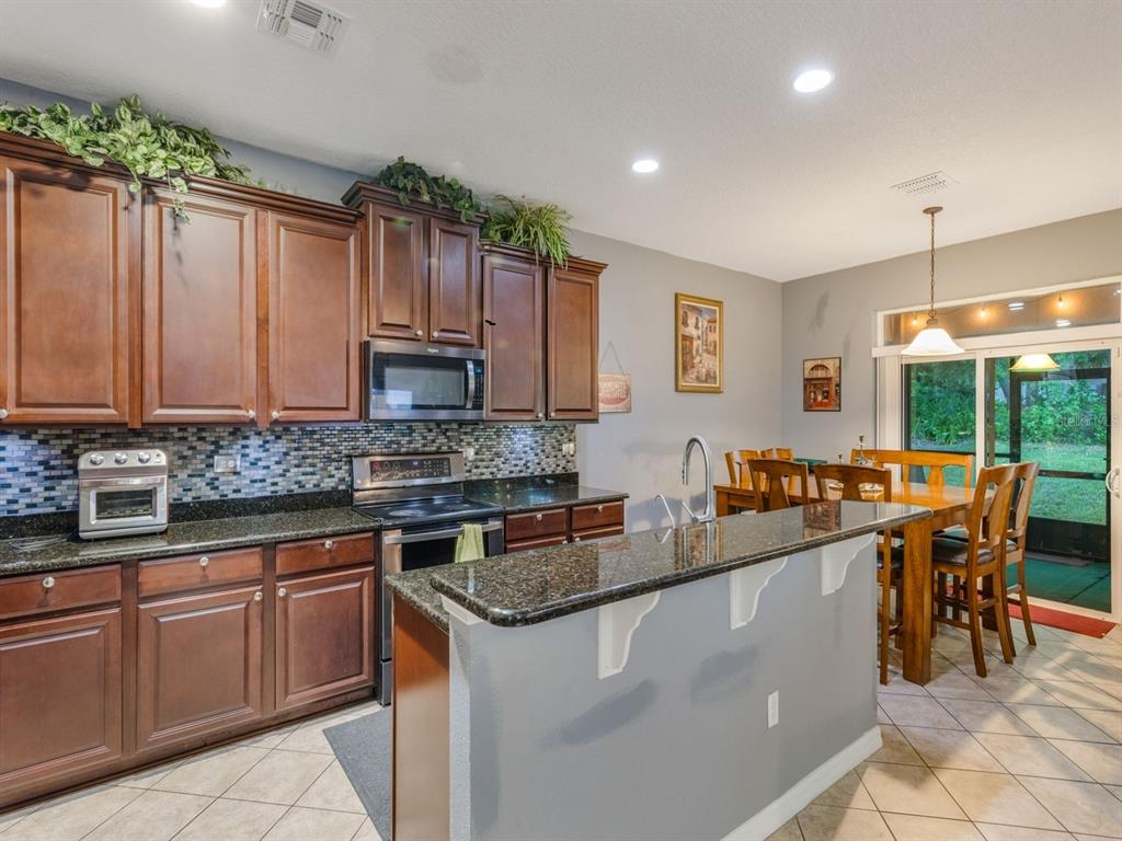 925 Counts Crest Circle Apopka, FL 32712 - Photo 14 of 36 a kitchen with kitchen island granite countertop a sink stove and cabinets