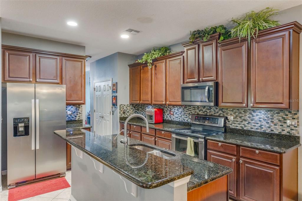 925 Counts Crest Circle Apopka, FL 32712 - Photo 15 of 36 a kitchen with stainless steel appliances granite countertop a sink a stove and a refrigerator