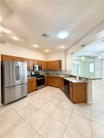 a large kitchen with a large counter top stainless steel appliances and cabinets
