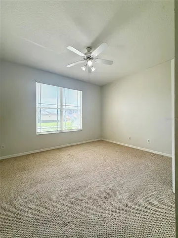 an empty room with a ceiling fan and window