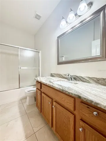 a bathroom with a granite countertop sink a toilet and a mirror