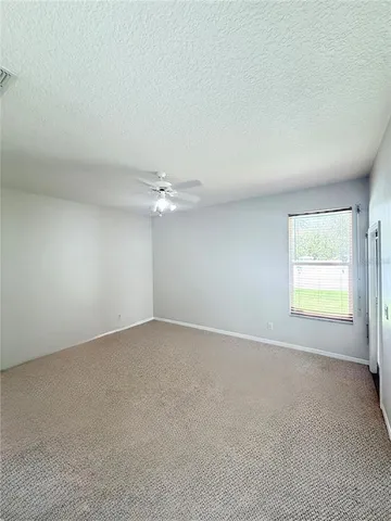 an empty room with a window and ceiling fan