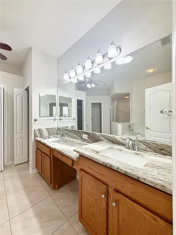 a bathroom with a granite countertop double vanity sink and a mirror