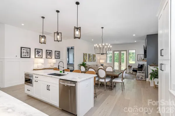 a view of a dining room and livingroom with furniture wooden floor a chandelier