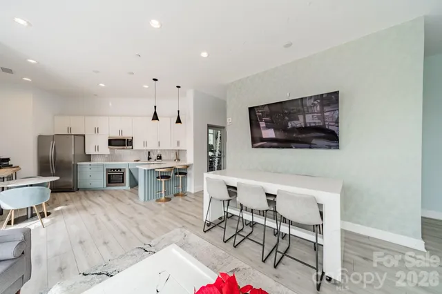 a living room with stainless steel appliances furniture a flat screen tv and kitchen view